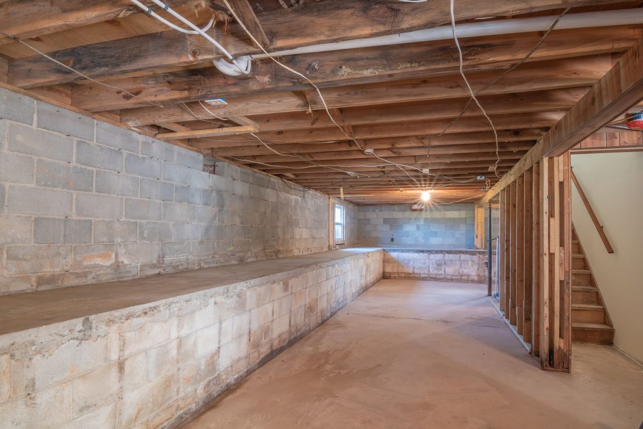 Unfinished basement with a raw concrete slab and exposed joists