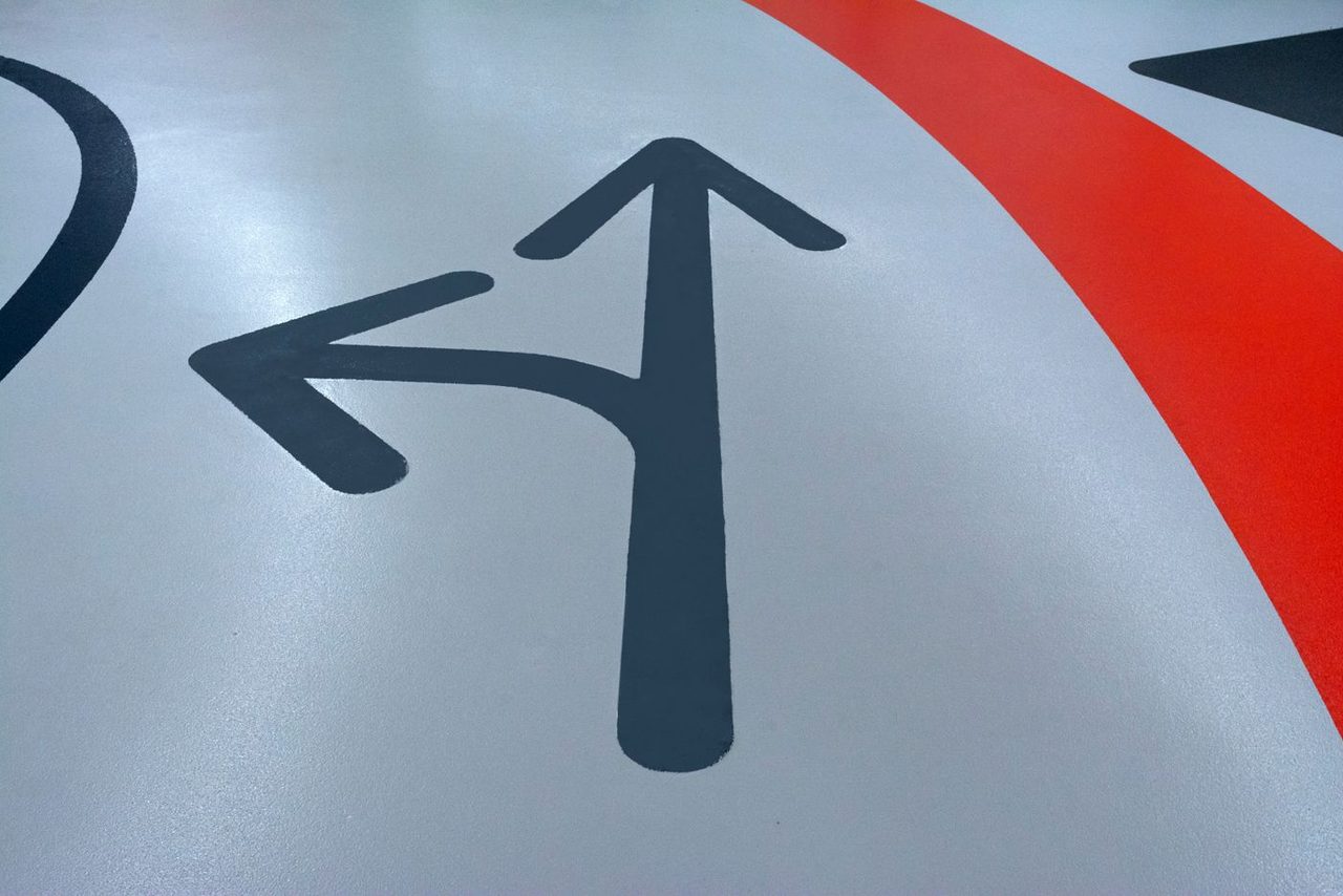 Close-up of a coated commercial floor with painted directional arrows and safety striping