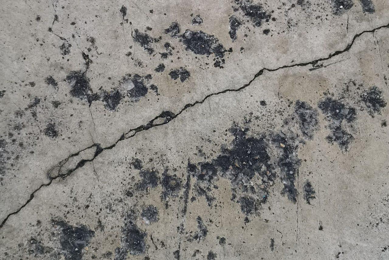 Cracked, pitted and stained concrete slab in Central Illinois before grinding and repair